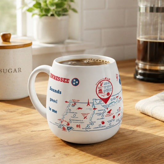 White mug with a Tennessee map design to track trips and experiences placed on a wooden kitchen counter with coffee.
