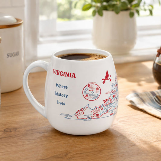 White mug with a Virginia map design to track trips and experiences placed on a wooden kitchen counter with coffee.
