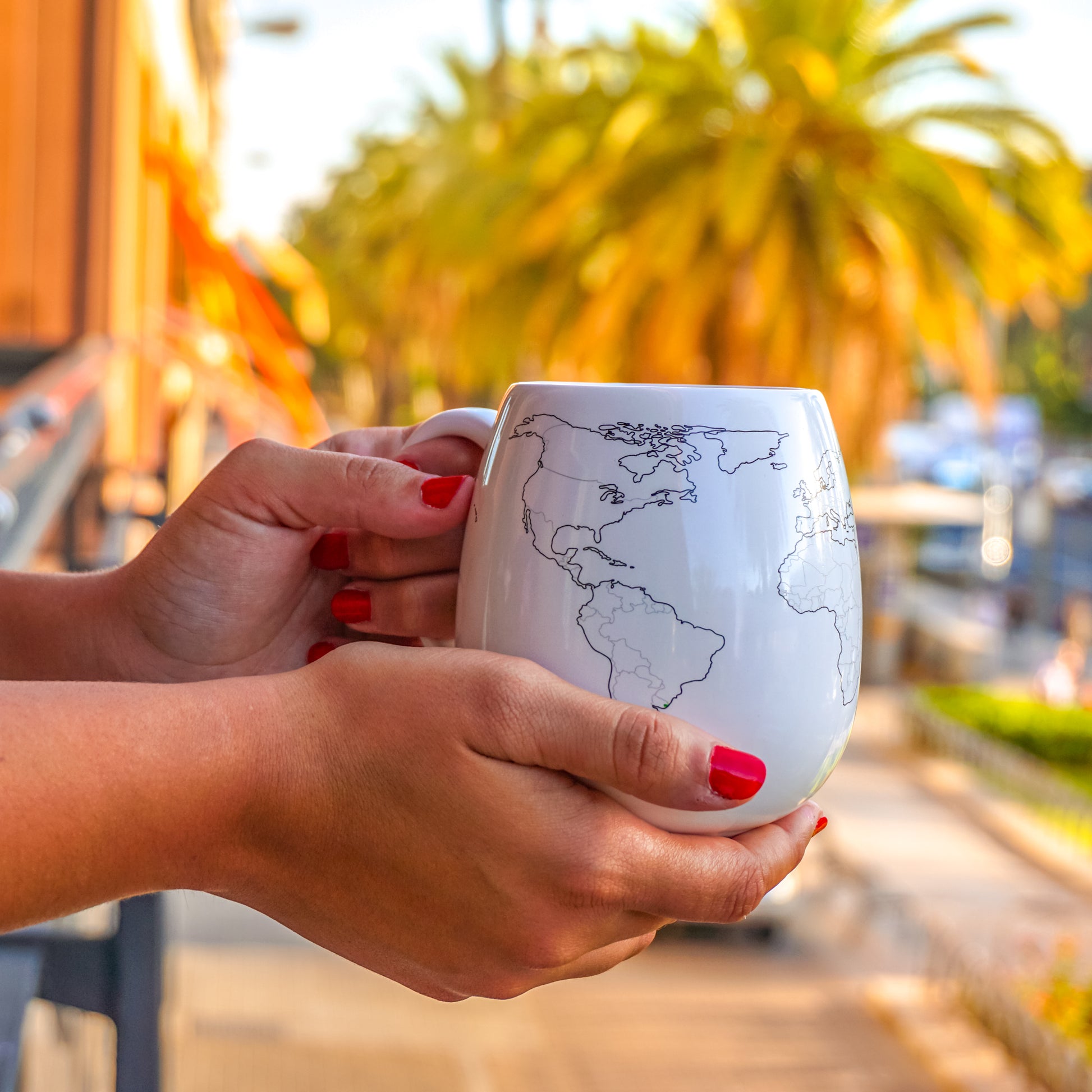 Hands holding a world map colour-in mug ready to mark countries visited, interactive travel tracker mug
