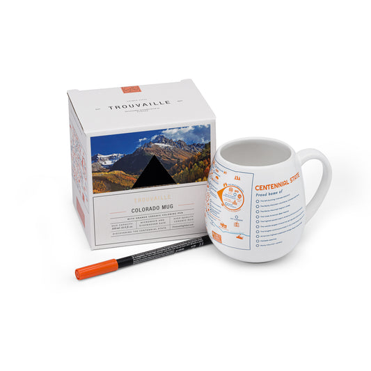 A white travel mug with a color-in map of Colorado, accompanied by an orange ceramic pen and packaging, mountain adventure souvenir for hikers and skiers