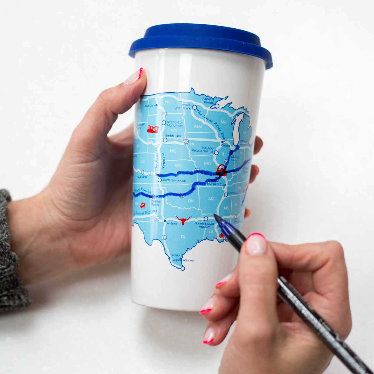 Coloring in routes on the USA road trip travel cup with a bue ceramic pen, interactive travel memory keepsake