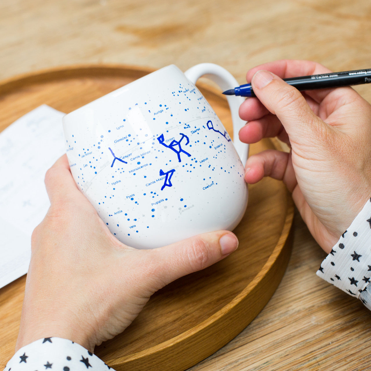 Colouring constellations on stargazing mug with blue ceramic pen, relaxing astronomy activity at home