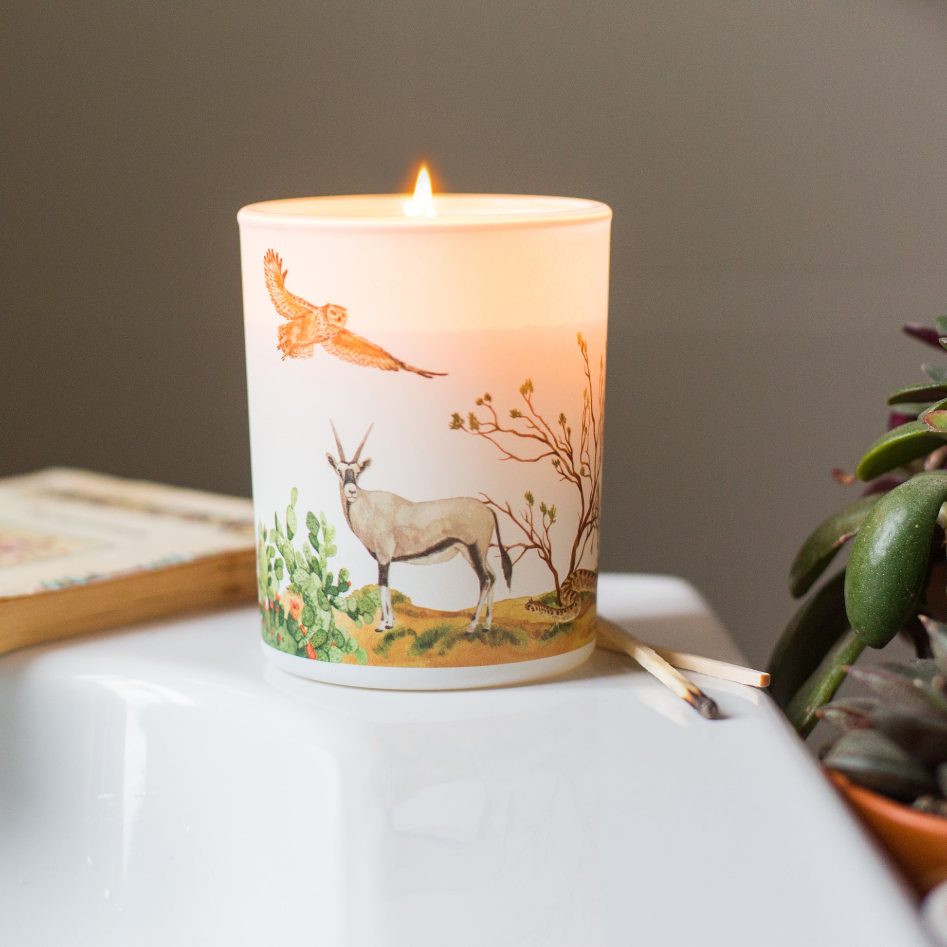 Lit desert soy candle with warming cinnamon and bergamot scent, eco-friendly candle inspired by golden desert scenery.