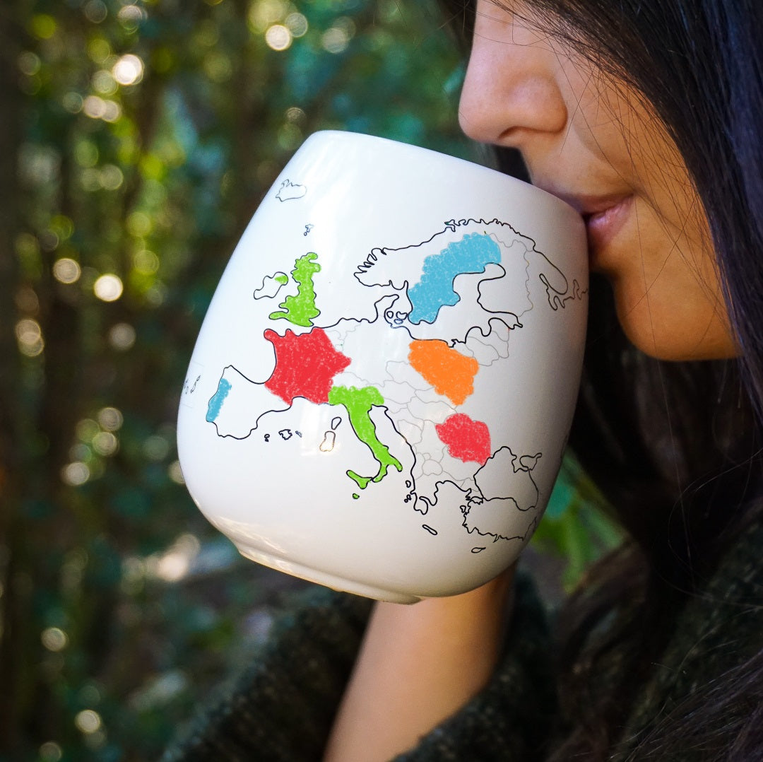 Woman drinking from personalised Europe travel mug with coloured countries, travel memories gift