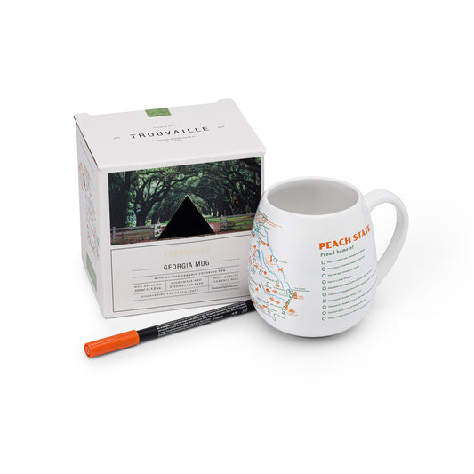 A white travel mug with a map of Georgia printed on it, alongside an orange ceramic pen and its packaging, Atlanta and coastal road trip memory gift