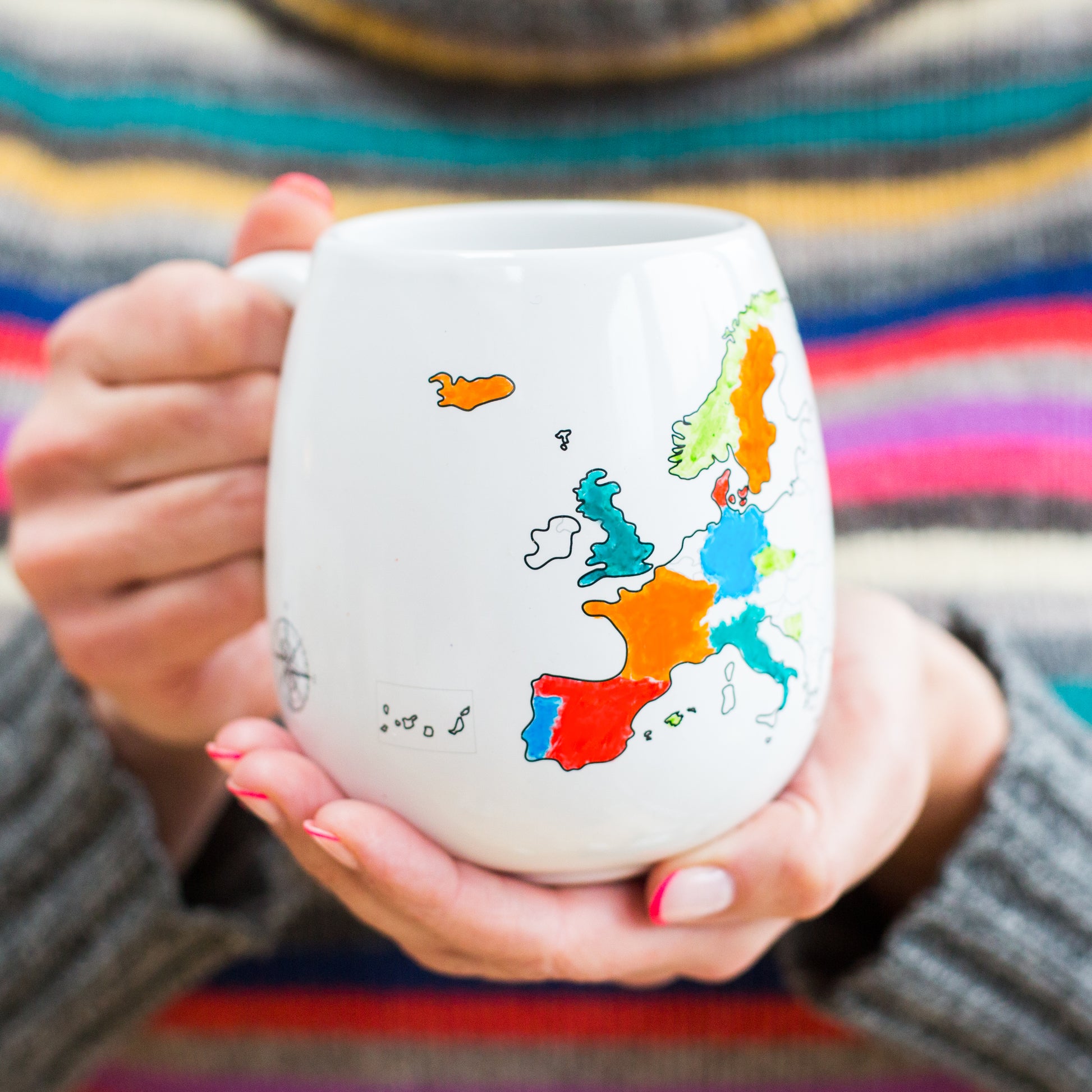 Hands holding coloured Europe map mug filled in with travelled countries, personalised Europe trip keepsake