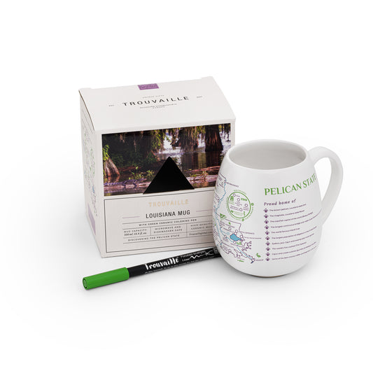 A white ceramic travel mug with a colorable map of Louisiana, accompanied by a green ceramic pen and its packaging