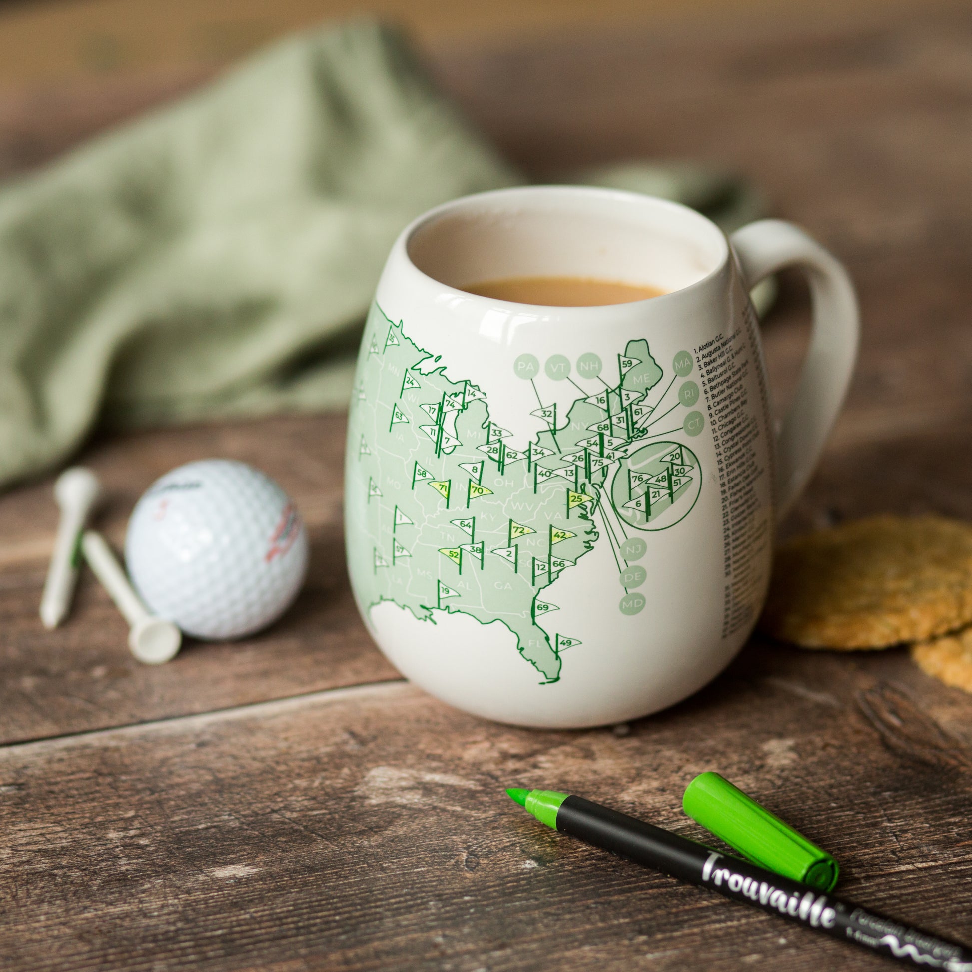US golfer’s map mug showing right side of golf courses checklist with ceramic pen and golf props on a wooden surface, gift idea for golfers