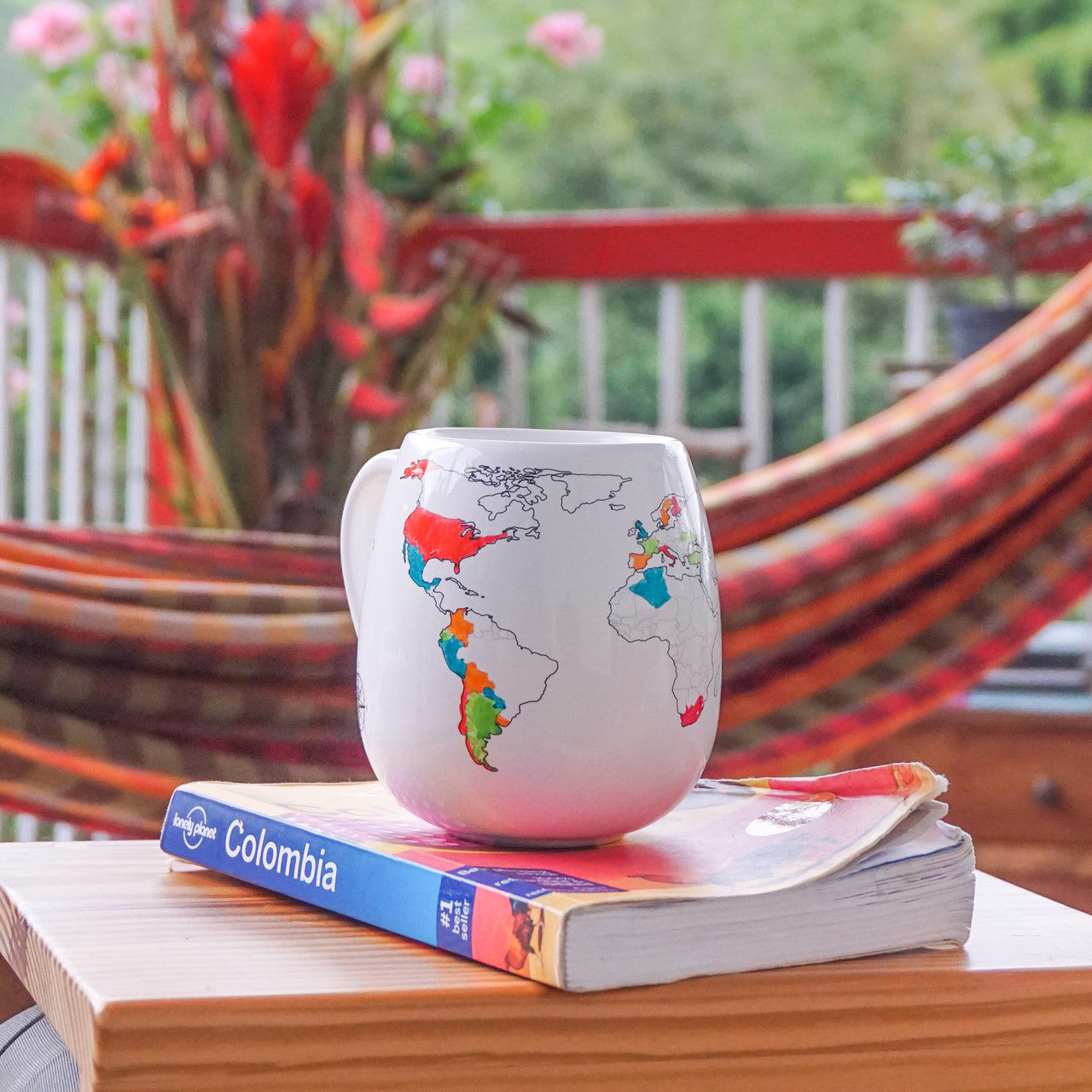 World travel map mug with coloured countries representing past adventures placed on top of a Lonely Planet travel guide